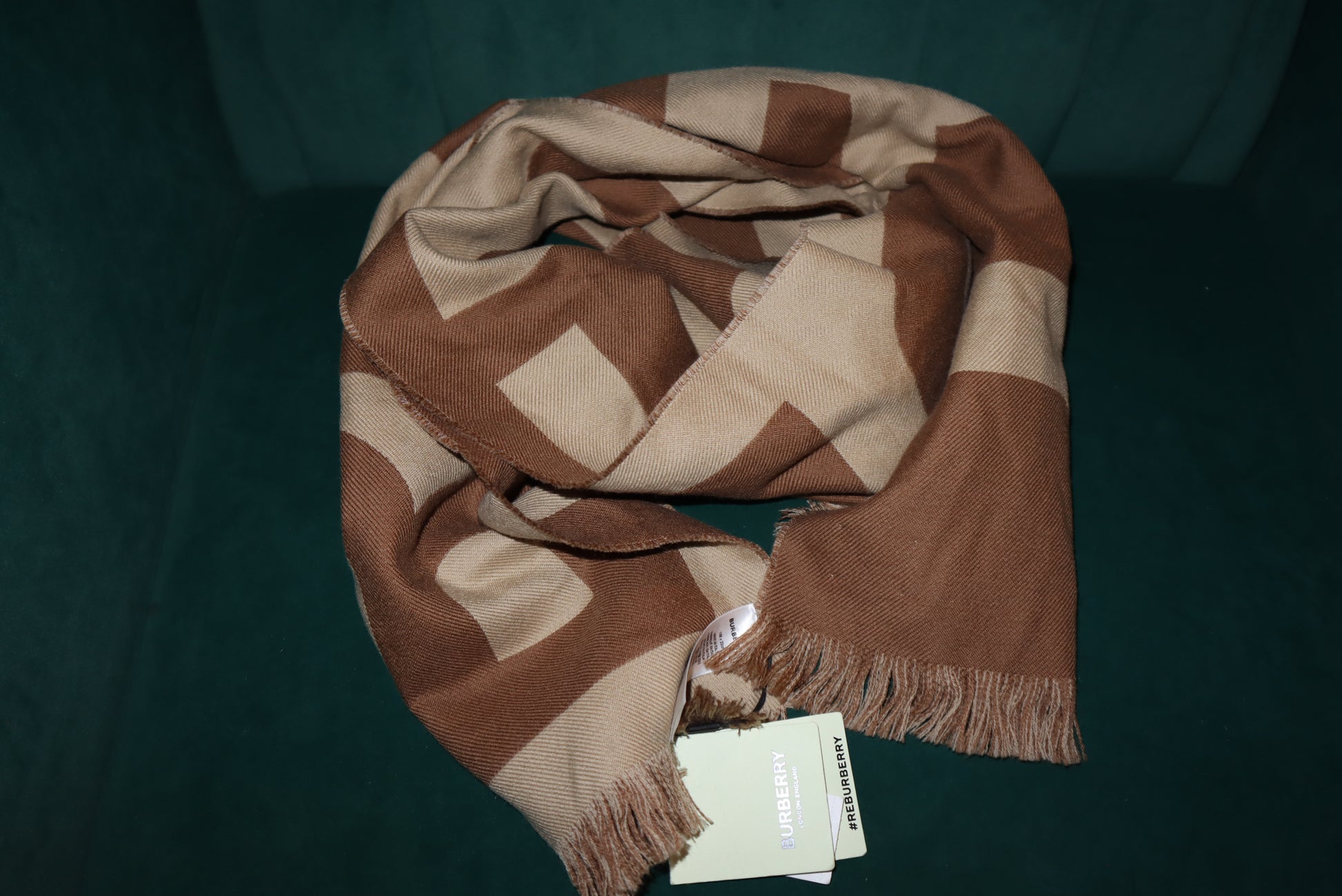 Brown and beige checkered scarf with a tag on a dark green background
