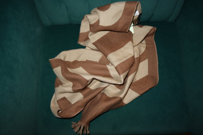Brown and beige patterned blanket on a green surface