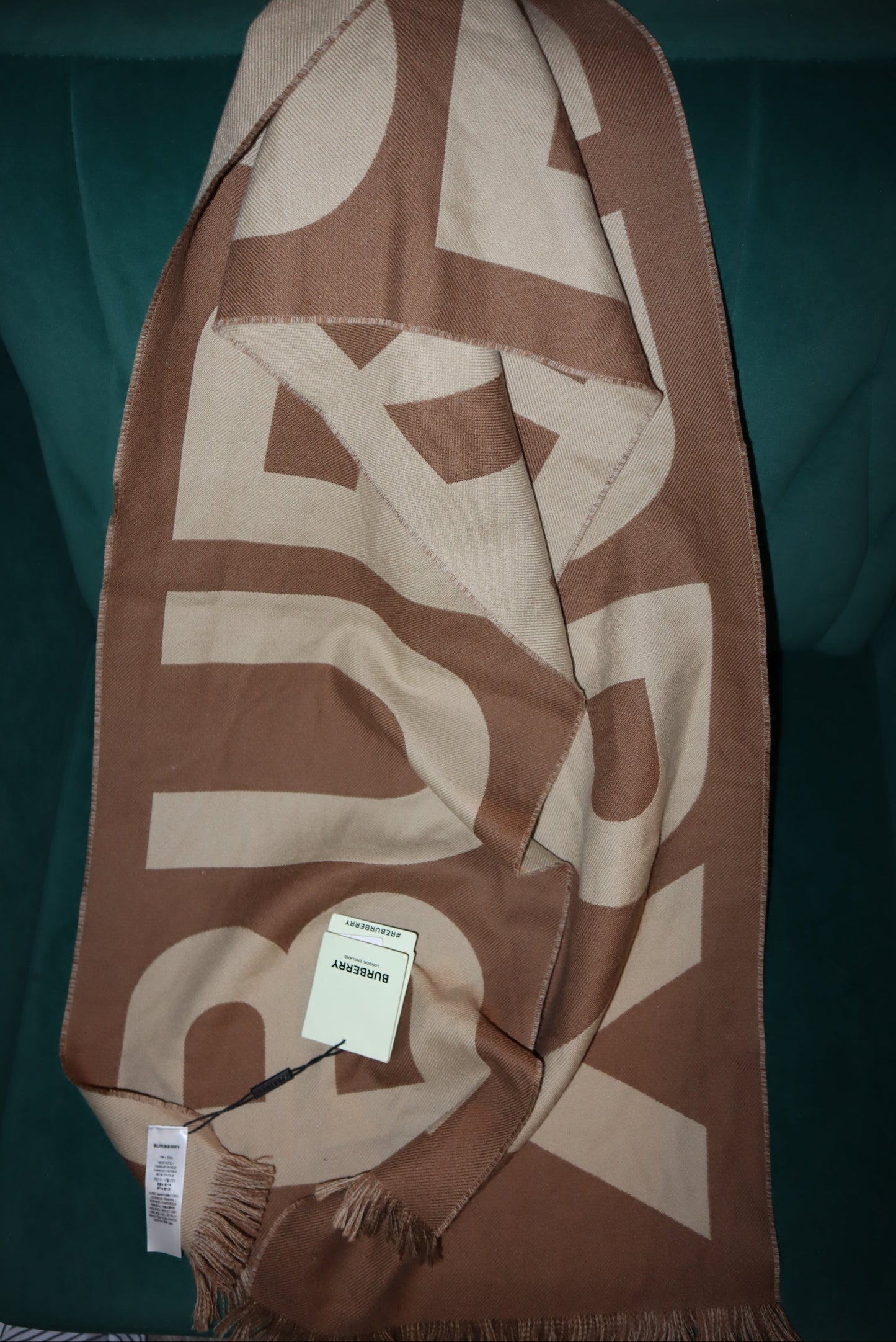 Brown and beige Burberry scarf with brand logo on a green surface